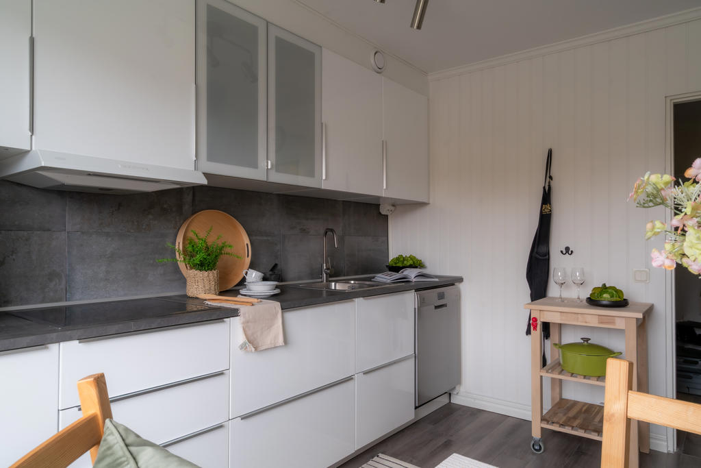 Grått kakel över arbetsytorna ger snygg effekt till det vita köket