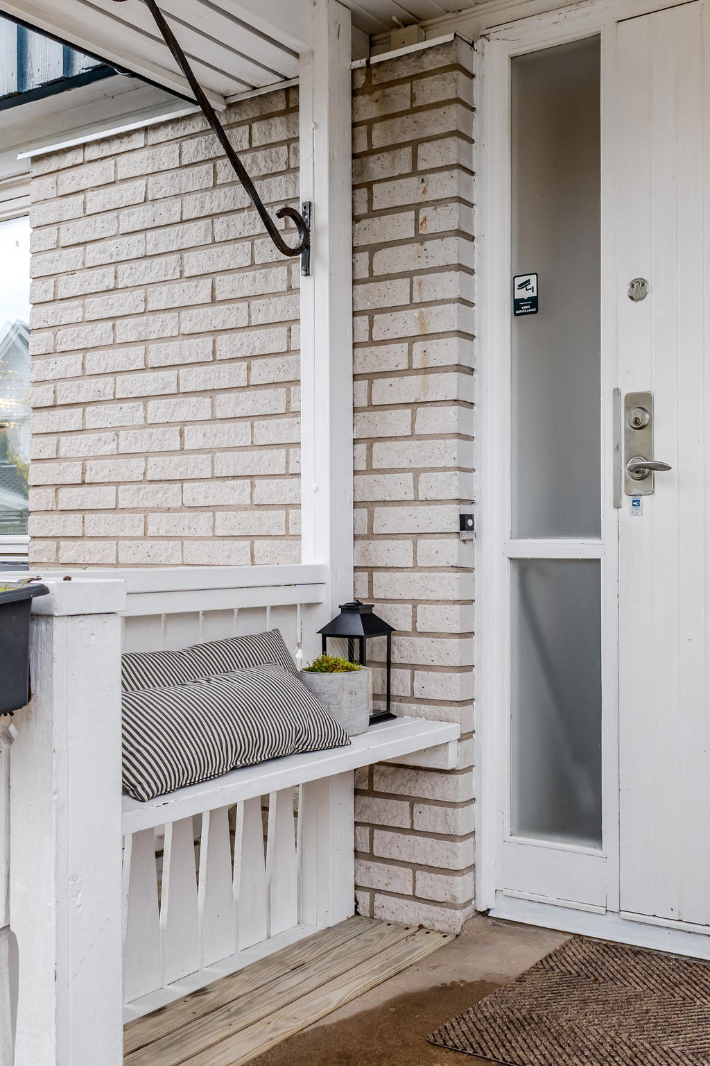 Inbjudande veranda vid entrén och plattsatt uteplats.