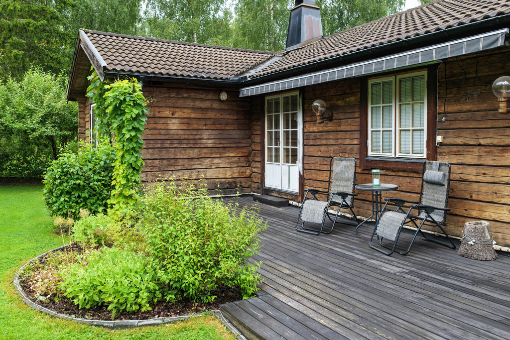 Trätrall i söderläge med markis och utgång från hallutrymme intill vardagsrum. 