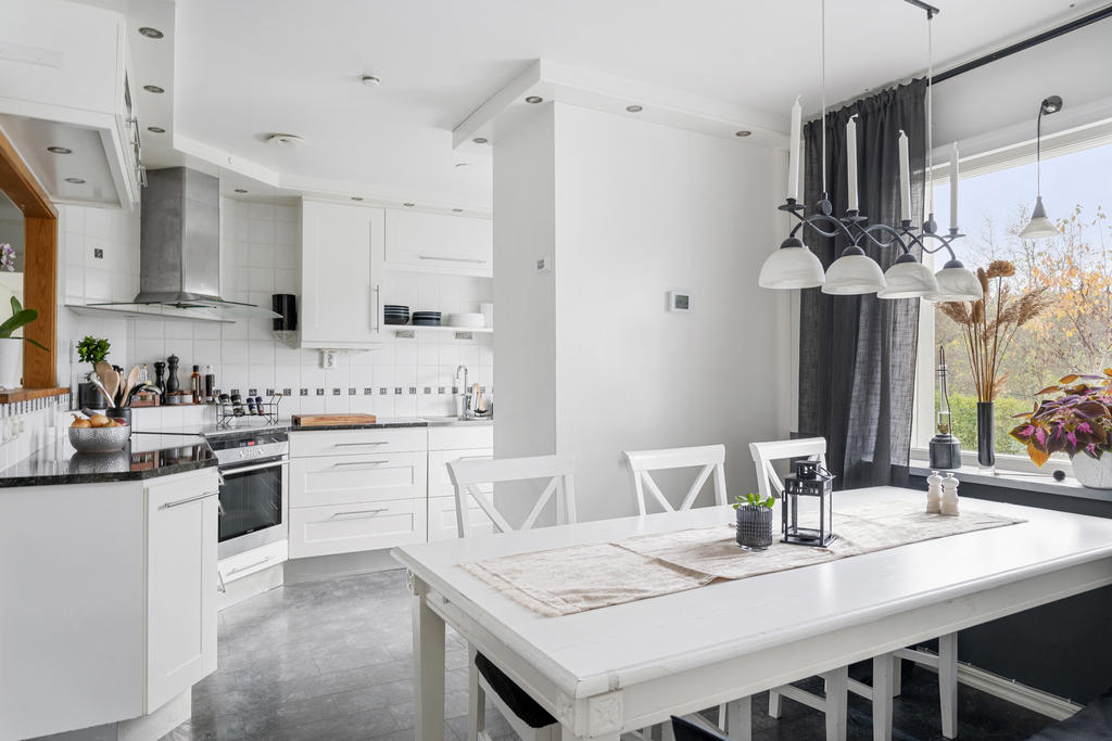 Köket är vitt och stilfullt. Praktiskt planerat med plats för köksarbete och förvaring