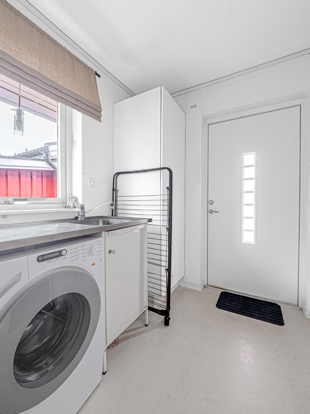 Tvättstuga med praktisk groventré mot garagesida