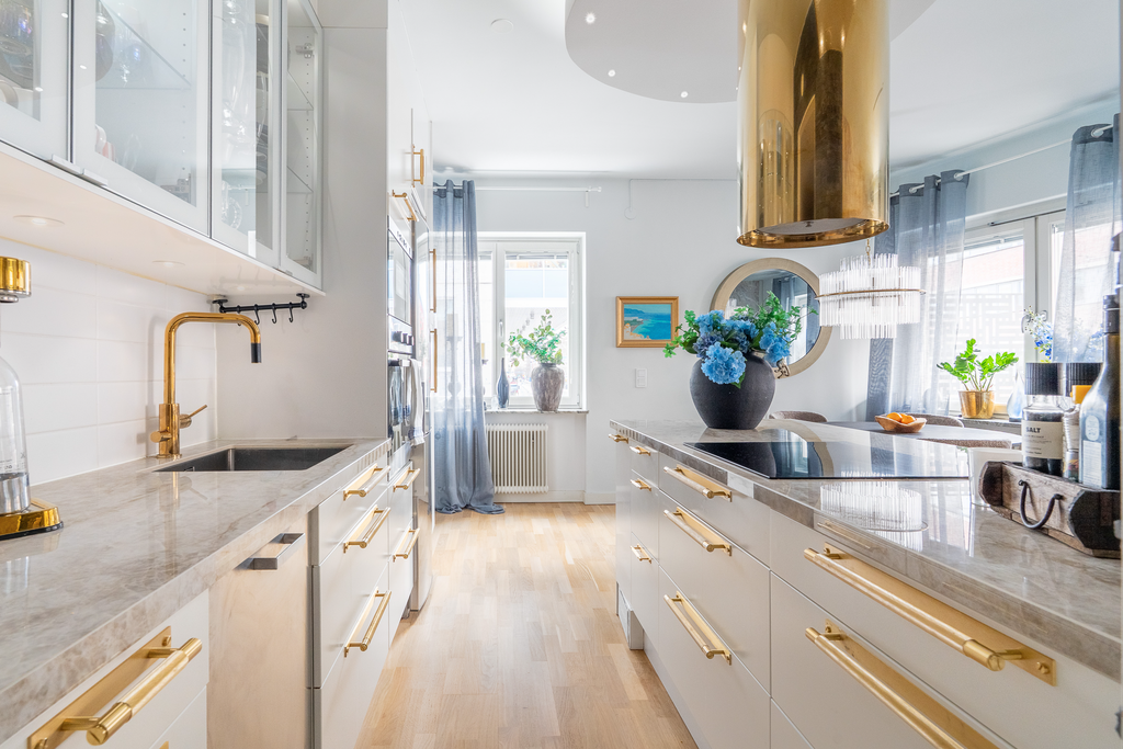 Ljust kök med stenskiva och gott om förvaring.