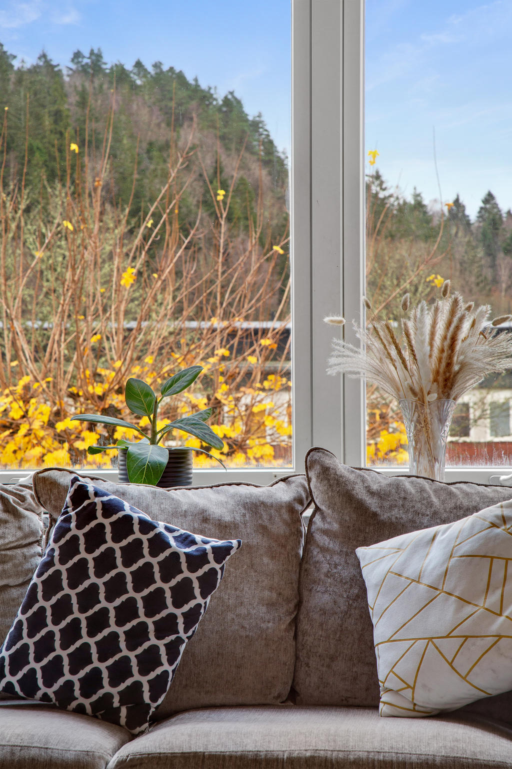 Stort fönsterparti i vardagsrum med utsikt mot innergård 