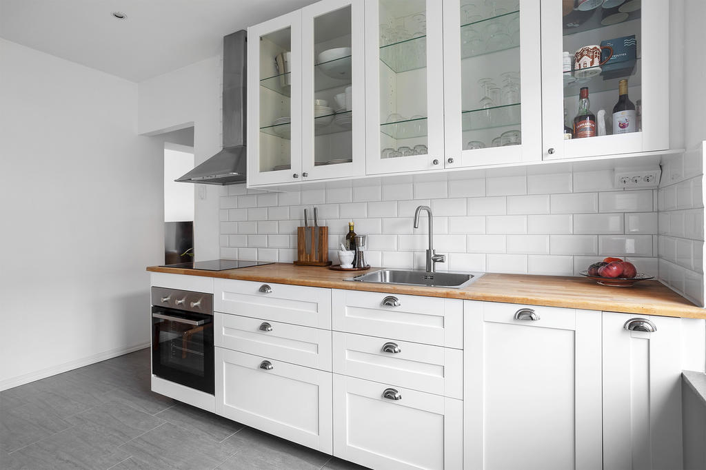 Ljust kök med gott om plats för matlagning och utrymme för liten matplats.