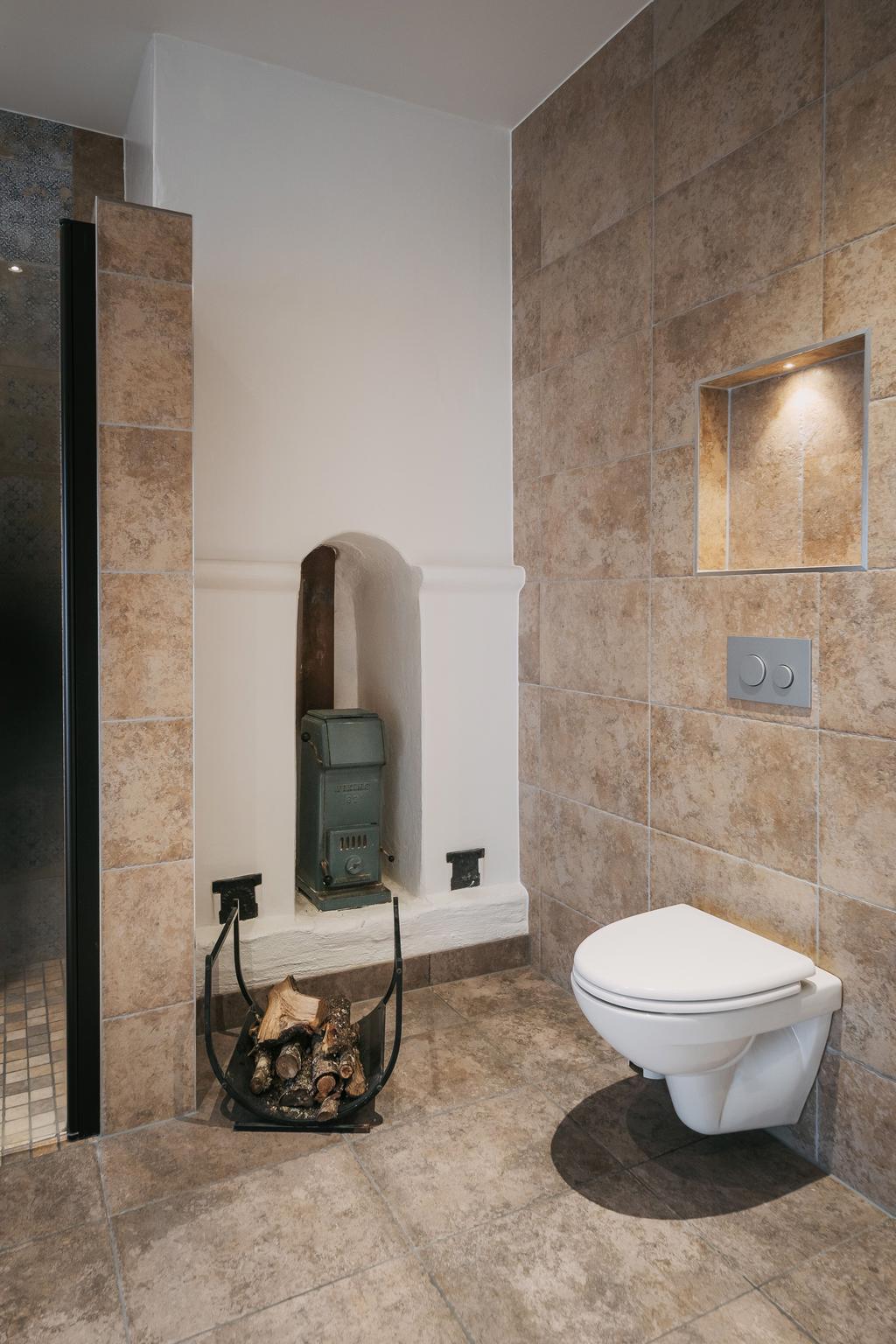 Den stilfulla kaminen ger badrummet en unik kombination av värme, lyx och avkoppling.