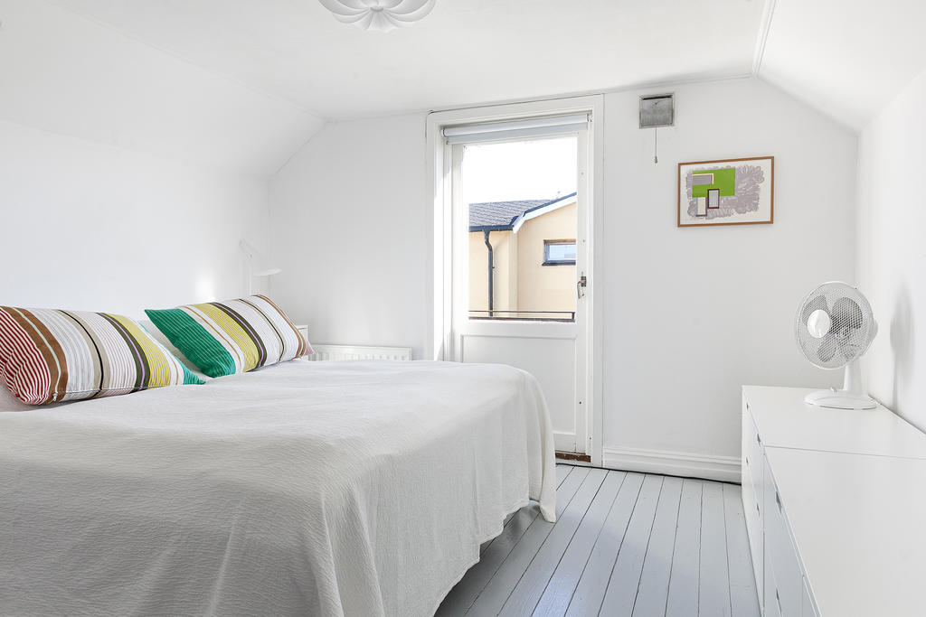 Generöst sovrum med samma vackra plankgolv och utgång till balkong