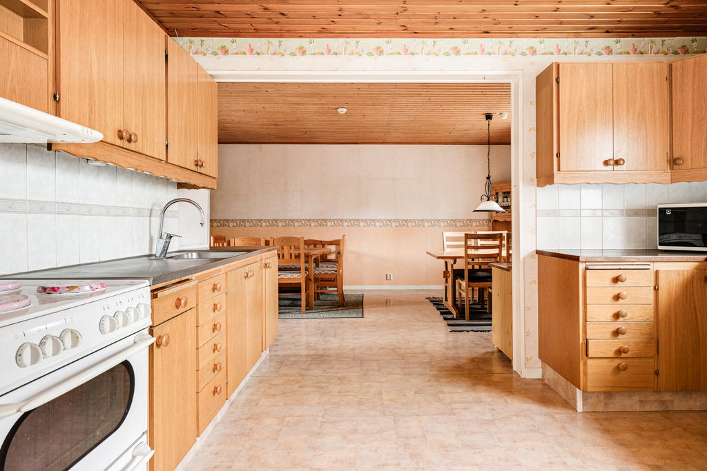 Rymligt kök med träluckor, plats för separat matplats och utgång till altan under tak. 