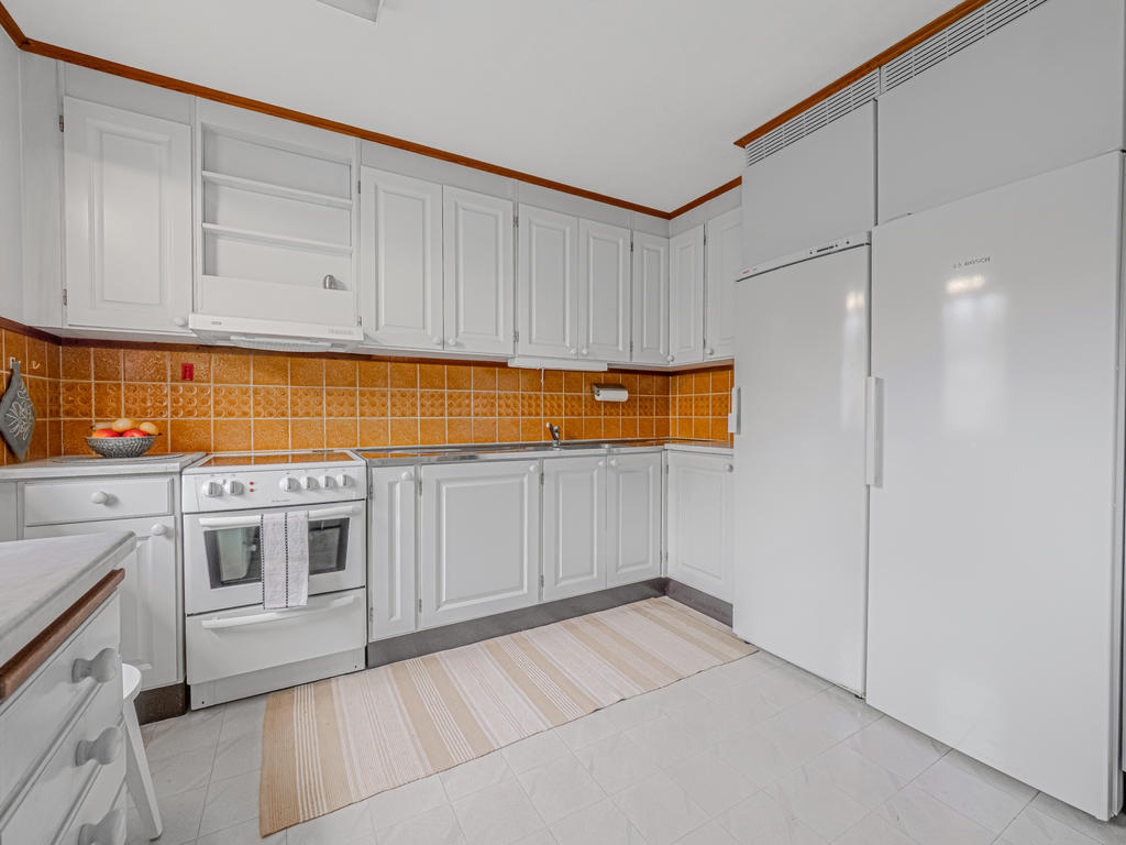 Ljust kök utrustat med kyl och frys i fullhöjd, spis och köksfläkt