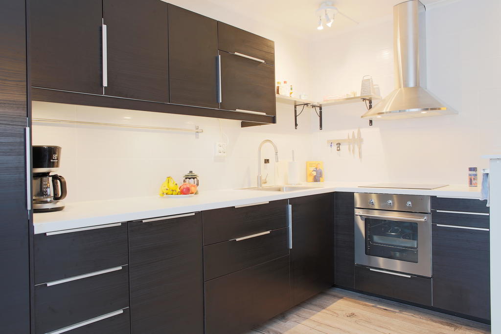 Mörkare skåpinredning från Ikea med ljus bänkskiva och kakel ovanför arbetsytorna