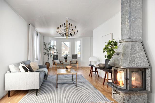 Hemtrevligt vardagsrum med täljstenskamin och burspråk