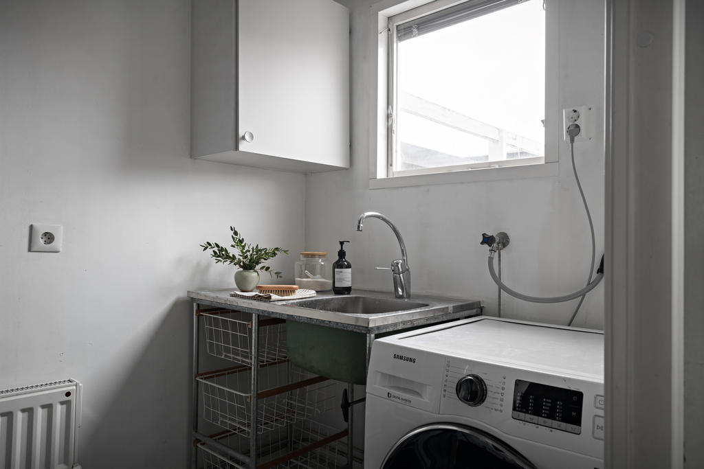 Praktiskt tvättstuga med förvaring, tvättmaskin och ho
