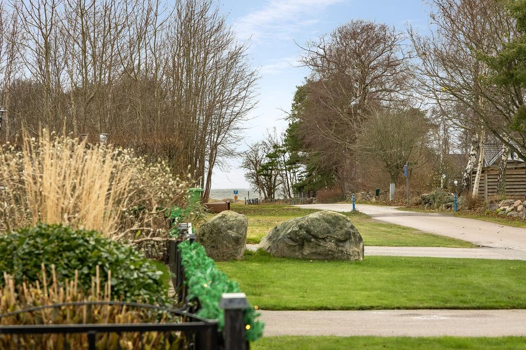 Tomt mot gatan med lummig omgivning, endast en kort promenad till stranden.