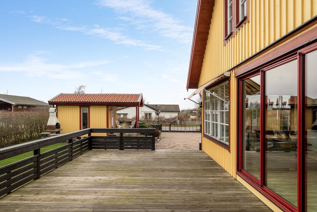 Husets gavel med uteplats och anslutande trädgård.