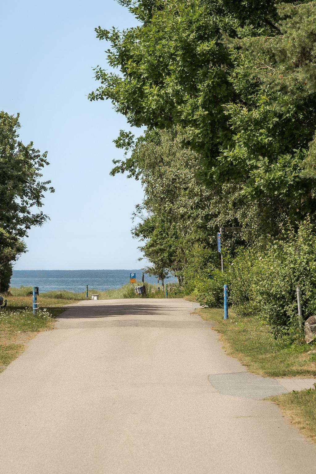 Tomt mot gatan med lummig omgivning, endast en kort promenad till stranden.