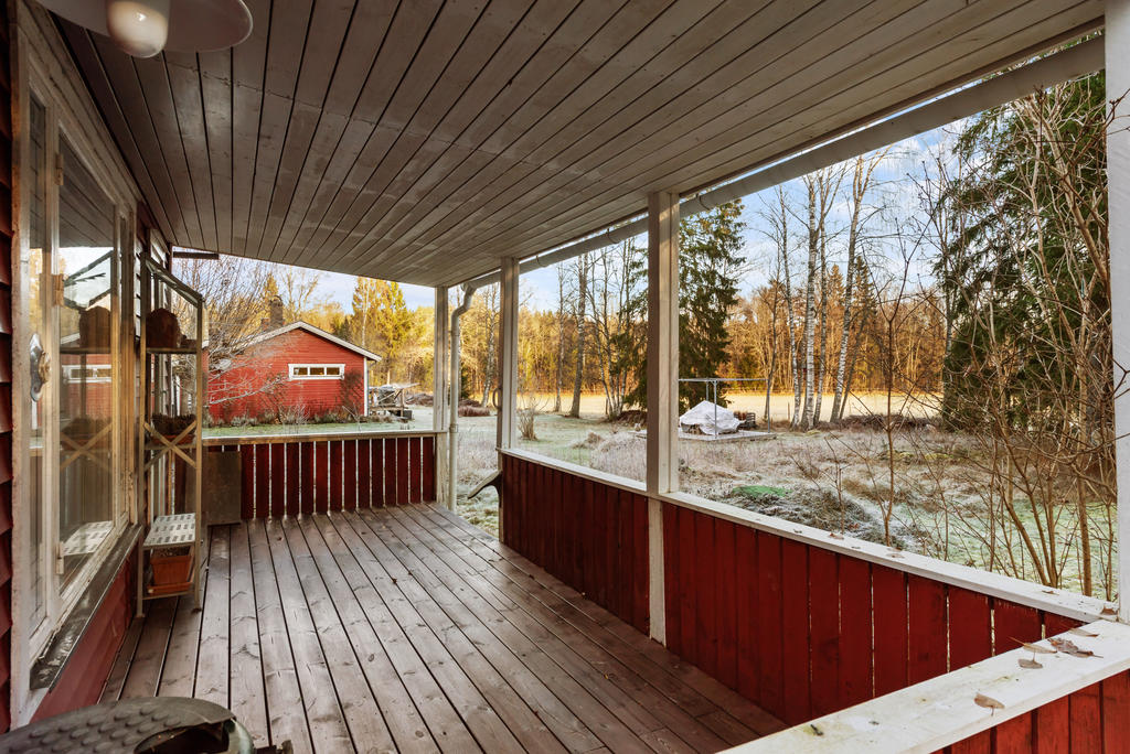 Träveranda under tak på husets gavel.