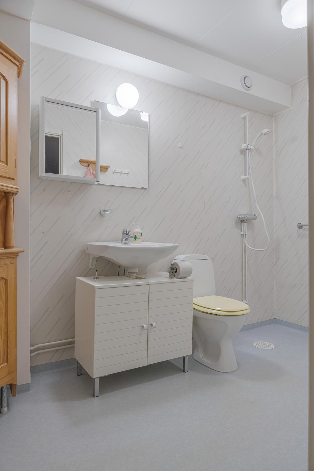 Ljust badrum utrustat med toalett, kommod och dusch samt goda förvaringsmöjligheter.