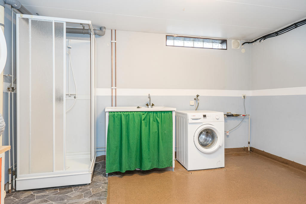 Tvättrum med tvättmaskin, torktumlare och dusch.