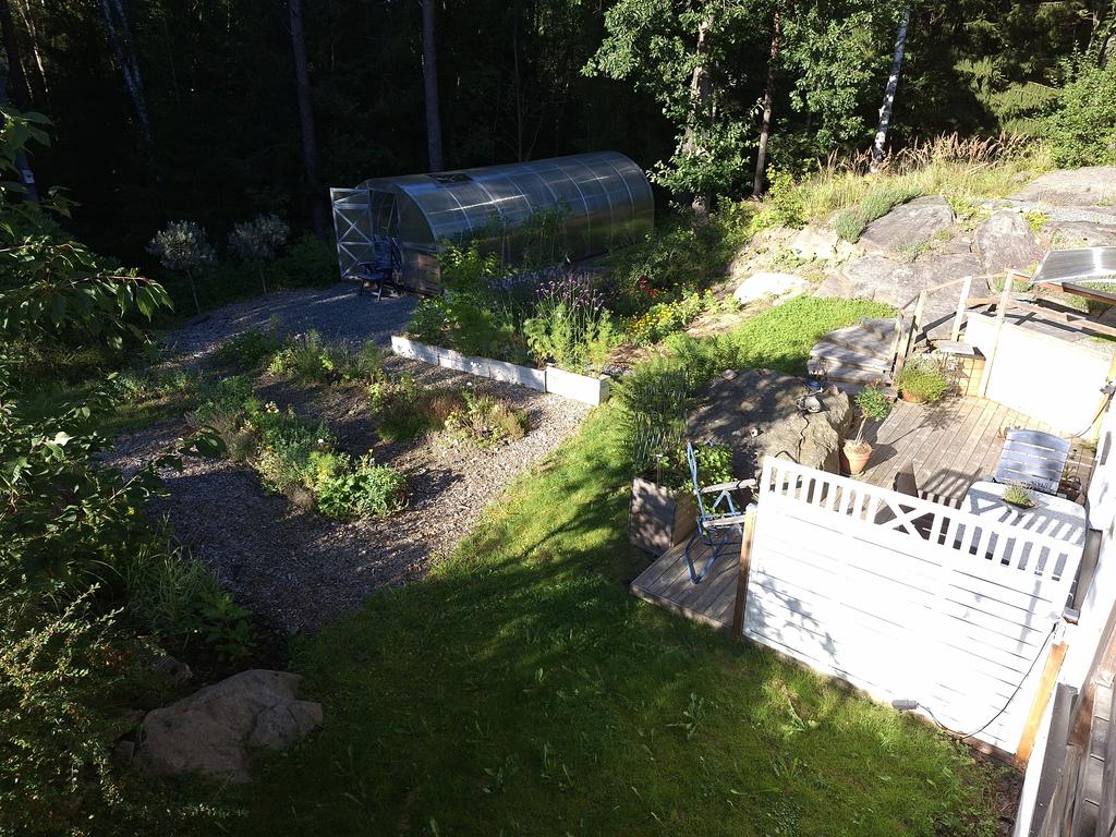 Altanen till lägenheten är helt separat , en bit ifrån altanen till huset. Bortanför syns det stora härliga växthuset!