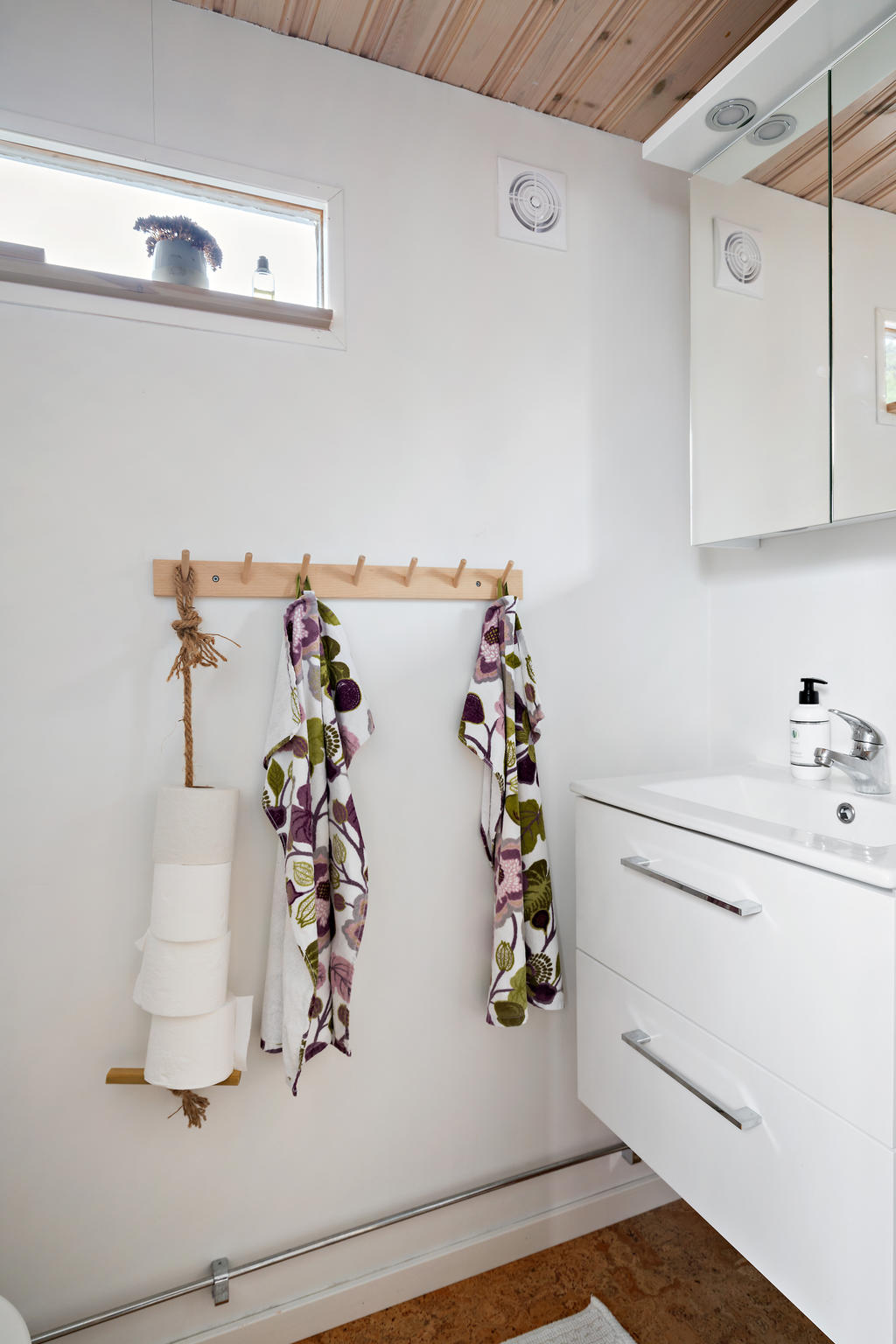 Fräsch toalettrum med toalett, handfat med kommod och spegelskåp. Fint ljusinsläpp