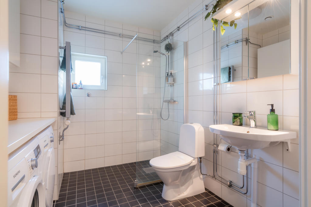 Stort badrum med dusch och glasvägg samt ett litet fönster