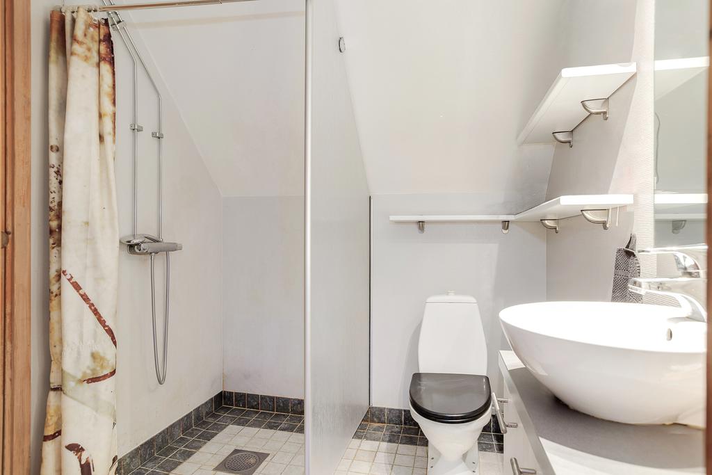 Halvkaklat badrum med kommod och dusch