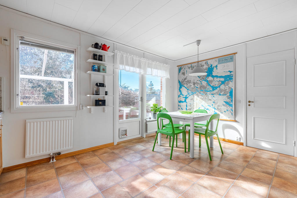 Rymligt kök med matplats och utgång till uteplats med pergola.