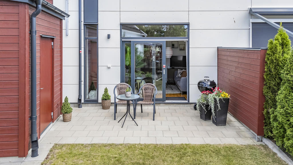 Stenbelagd uteplats med grönytor och förråd 