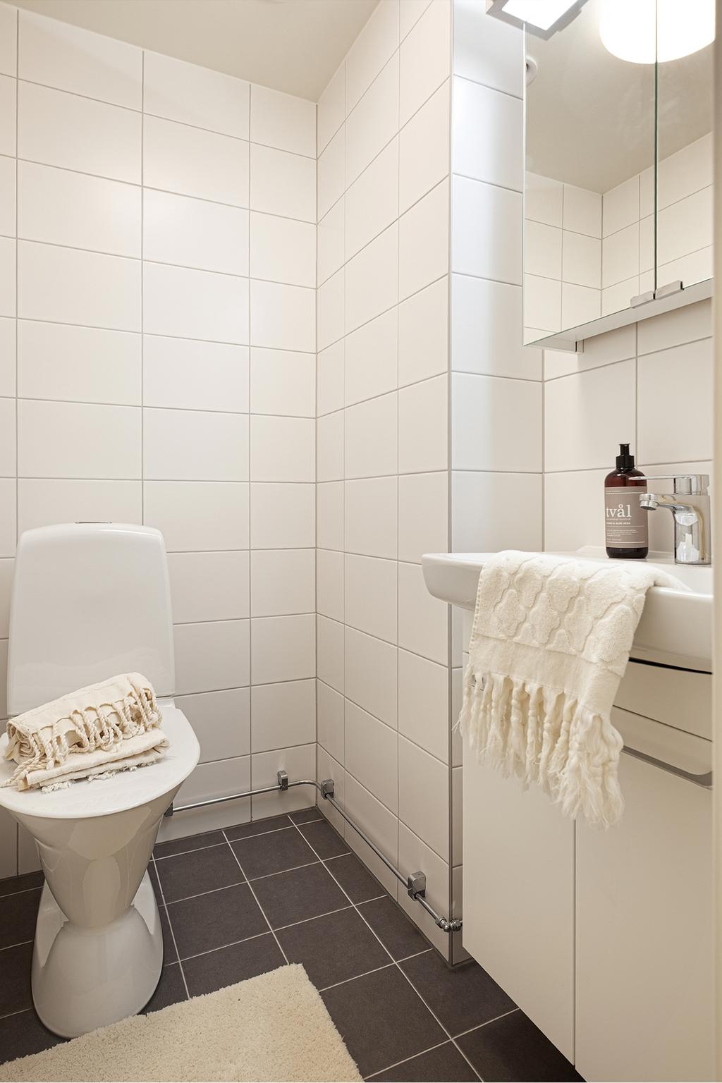 Gästtoaletten är strategiskt placerad i hallen, ljus och fräsch. Plats för förvaringsmöbel finns