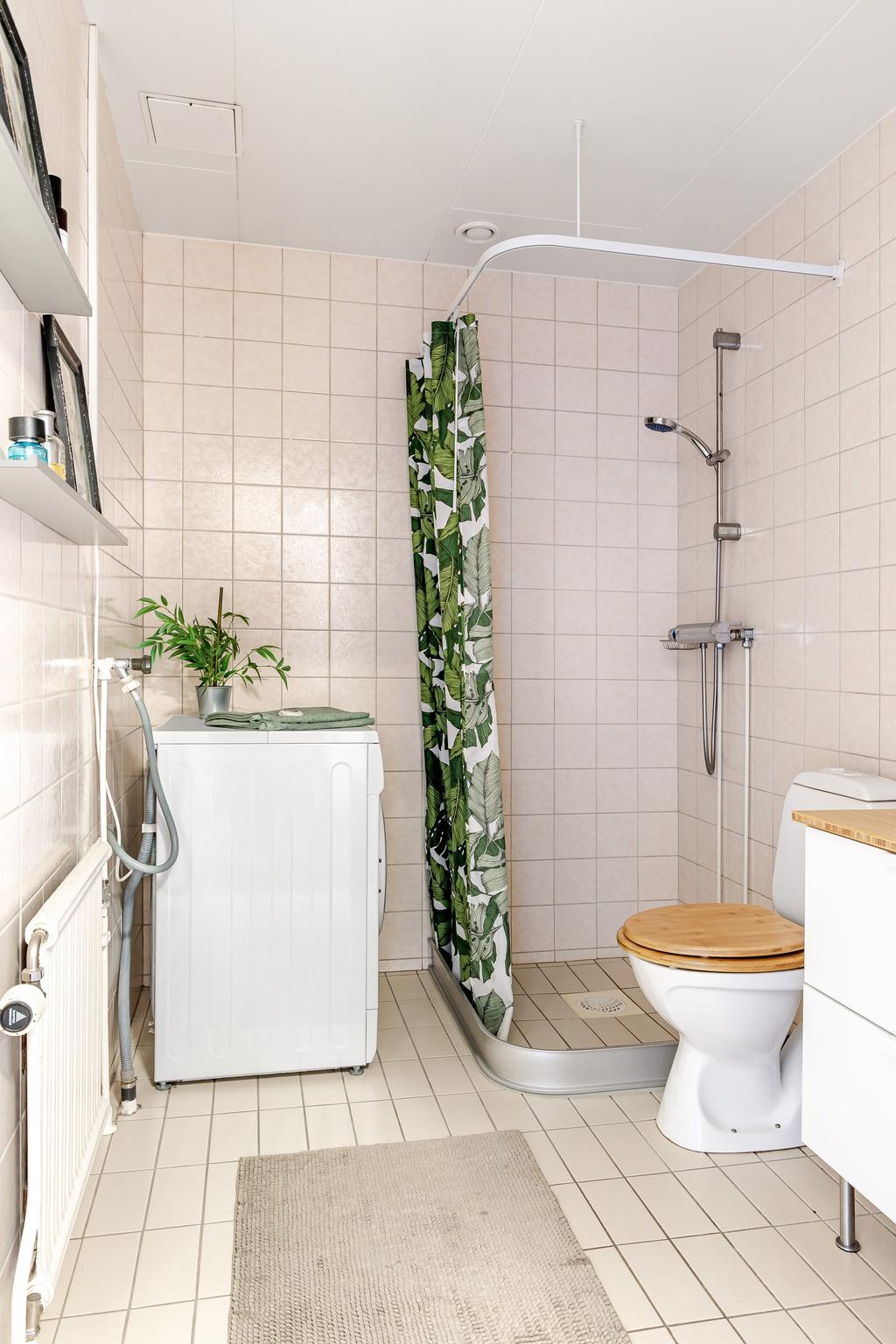 Fräscht badrum med dusch, helkaklade väggar och moderna detaljer.