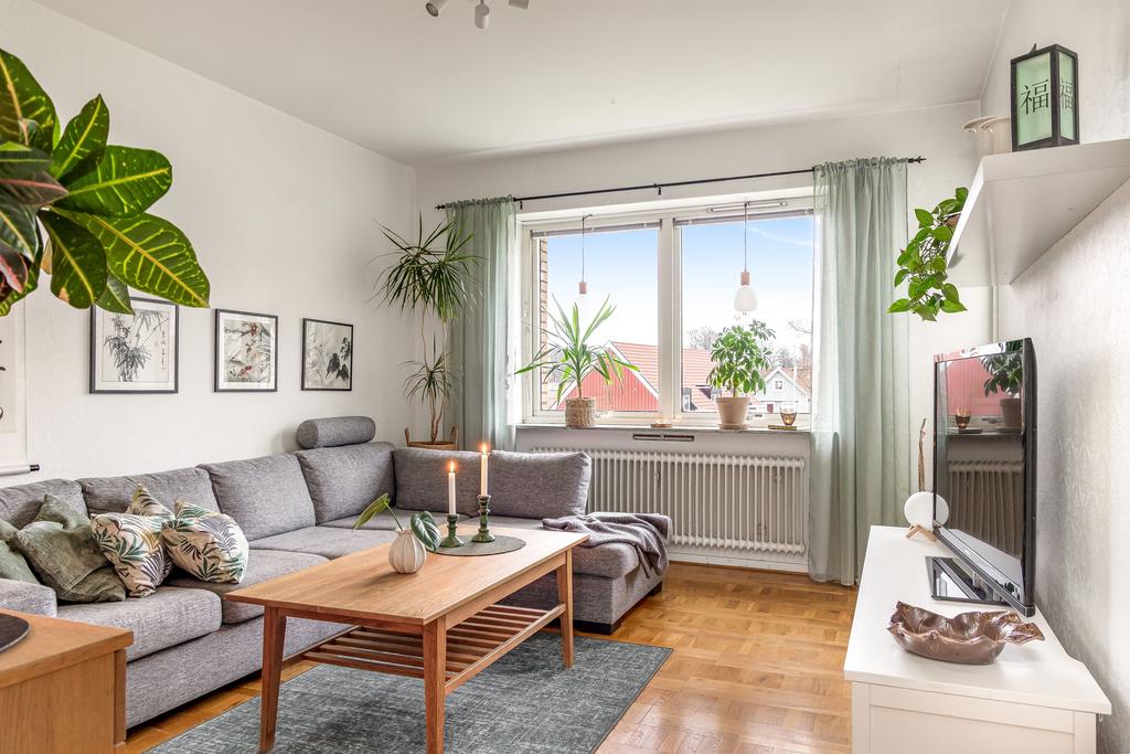 Ljust och luftigt vardagsrum med stora fönster och utsikt mot grönska.