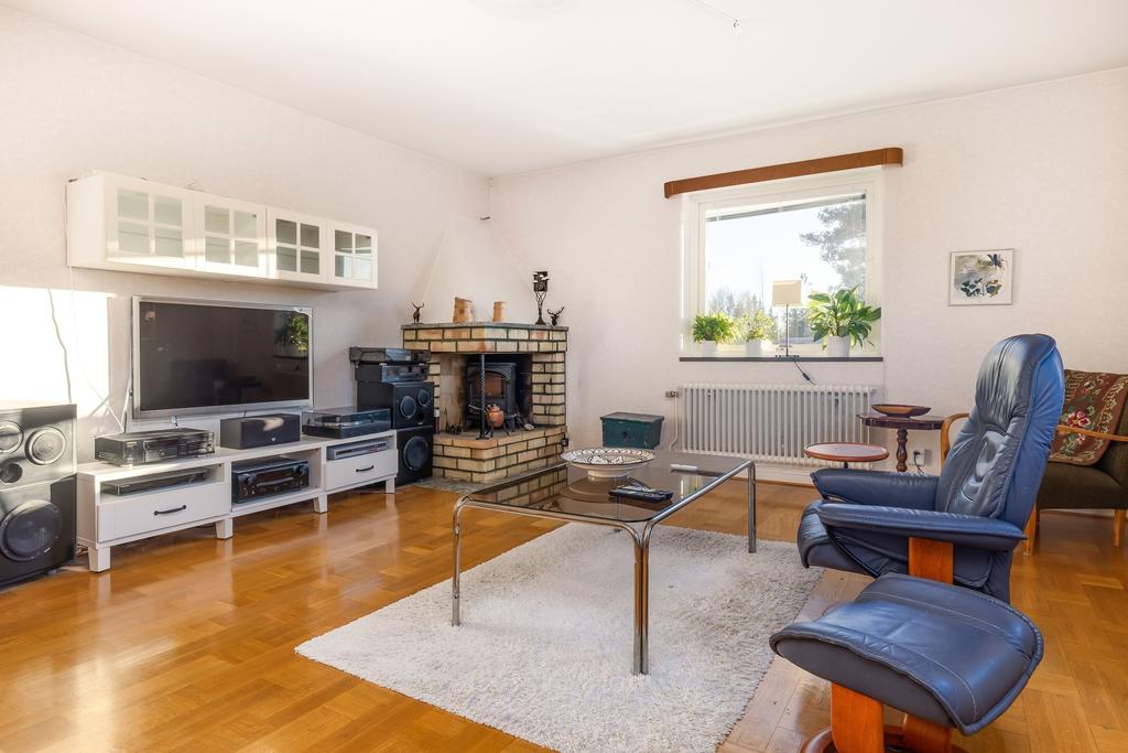 Vardagsrum med öppen spis samt utgång till balkong.