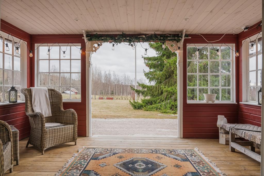 Inbjudande entré med plats för sittmöbler och utsikt mot tomten, vilket skapar en välkomnande övergång mellan ute- och innemiljö.