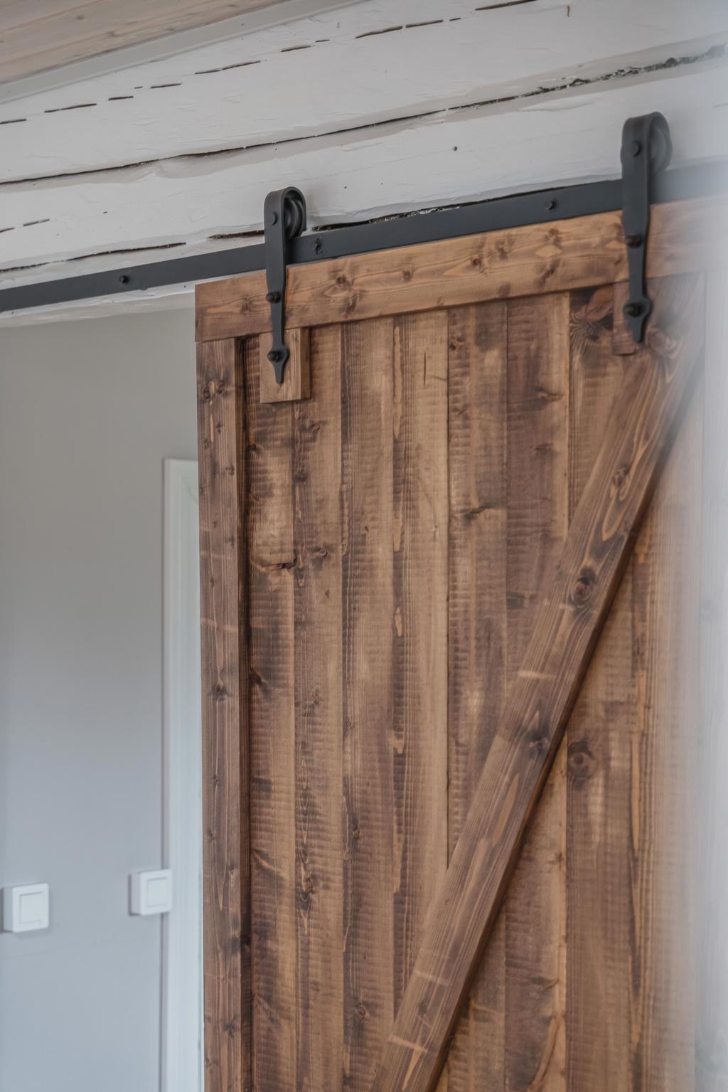 Detaljbild av skjutdörr i trä med synliga beslag som ger ett rustikt och gediget intryck.