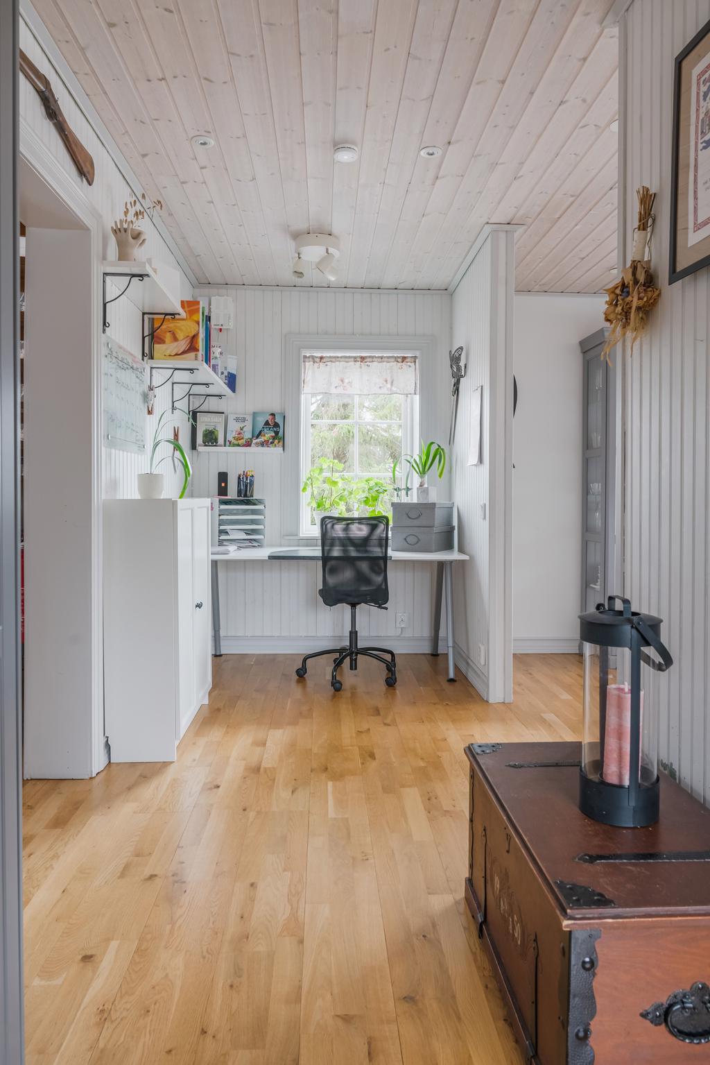 Kontorsplats i anslutning till kök och matplats, med praktisk arbetsyta och fint ljusinsläpp från fönster.