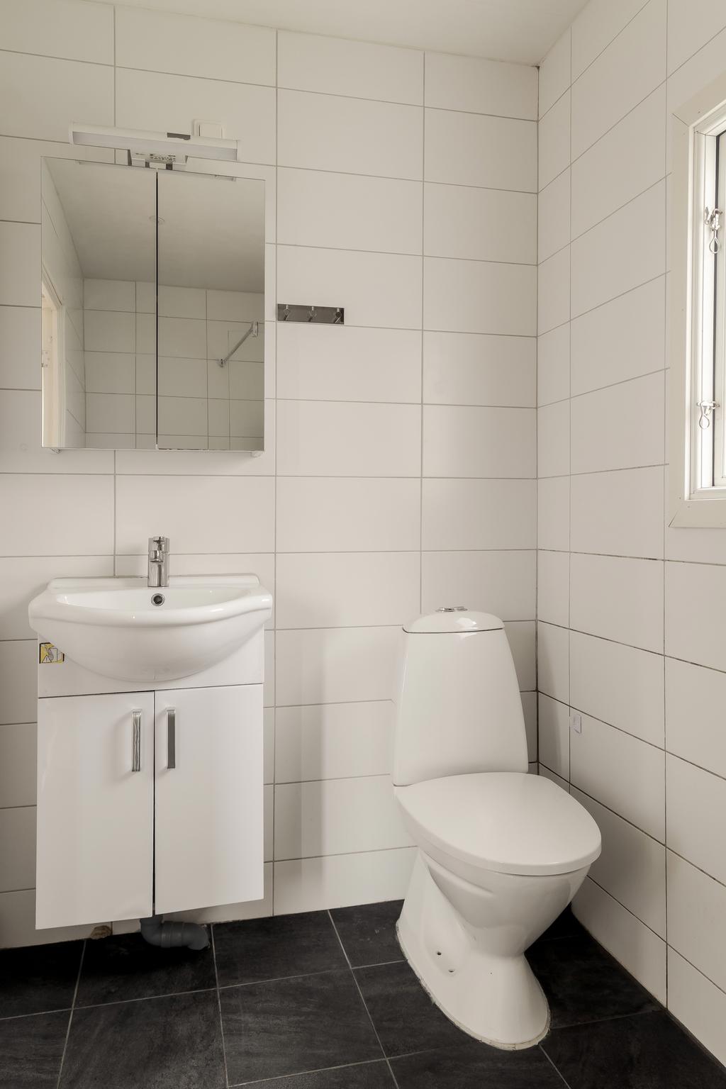 Badrum med wc, handfat och kaklade väggar.