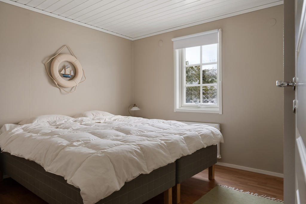 Detta charmiga sovrum på nedre plan erbjuder en lugn och avkopplande atmosfär. Här finns gott om utrymme för en bekväm dubbelsäng, praktiska sängbord och generösa garderober för förvaring. Ljuset flödar in genom fönstret och skapar en härlig inramning till detta vilsamma utrymme.