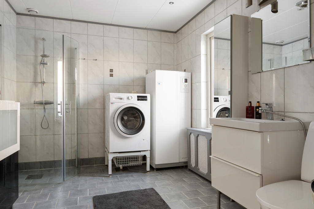 Kaklat badrum med dusch och tvättmaskin
