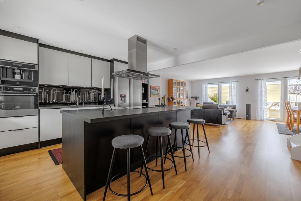 Öppna sociala ytor med kök, vardagsrum och matplats i en enhet. Stilrent kök med stor köksö, kaffemaskin och vinkyl mm. Två renoverade badrum och tre sovrum.