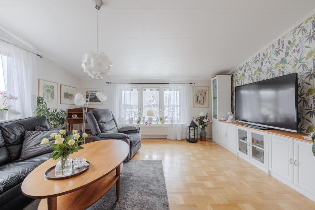 Det ljusa vardagsrummet bjuder på parkettgolv, öppen spis och stora fönsterpartier som ger en härlig vy över Gamlebyviken