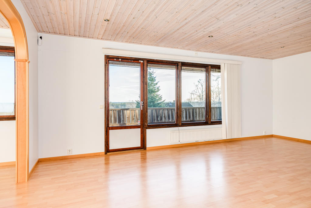 Lummigt vardagsrum med utgång till balkong.