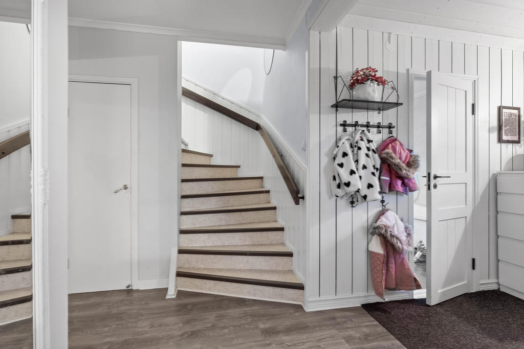 Hall med trapp till övervåning och ingång till badrum. 