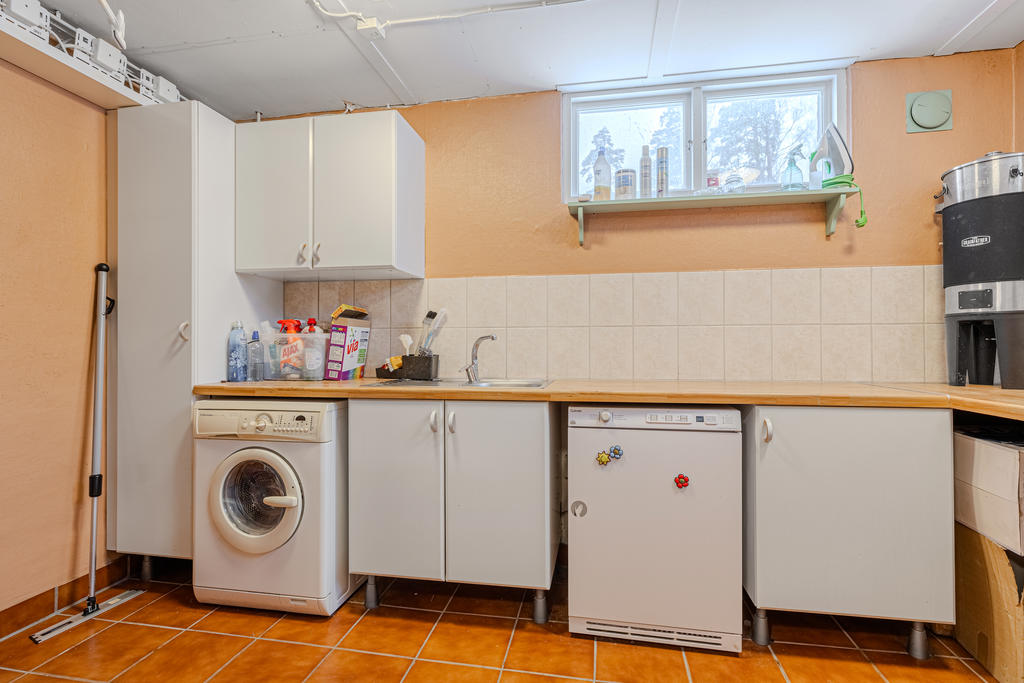 Tvättstuga med klinker på golv utrustat med tvättmaskin samt torktumlare 