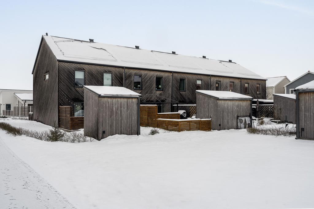 Baksida med terass och liten grästäppa samt trädgårdsbod