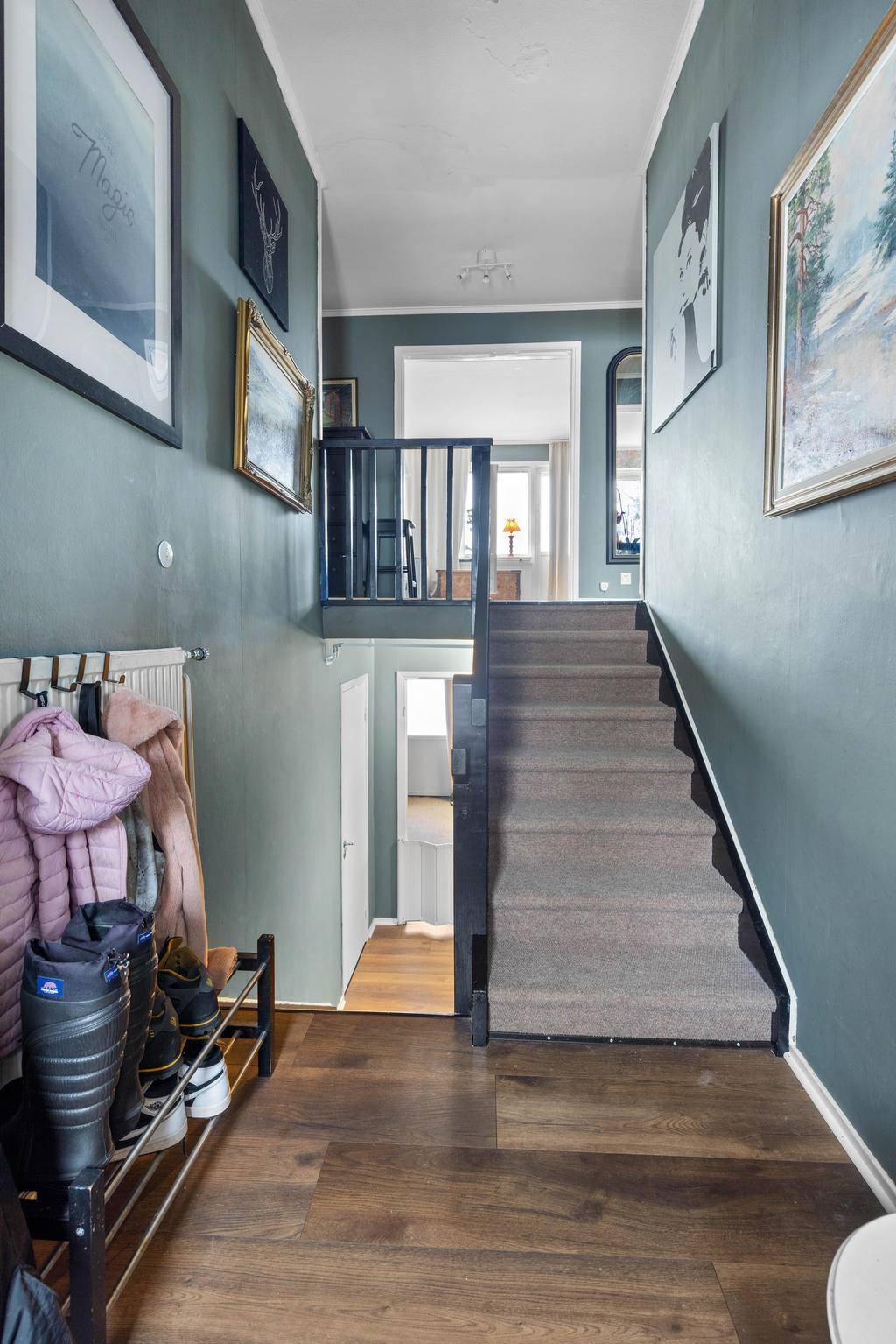 Vy från hallen med halv trapp ned till källarplanet och upp till övervåningen. 