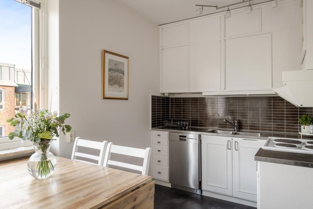 Ljus köksinredning med mörkbrunt kakel som fint bryter av