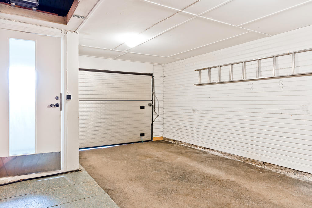 Garage med dörr in till hallen. I bild syns lucka till vind.