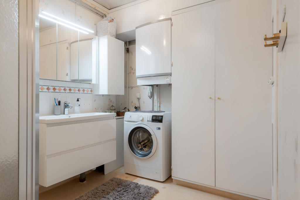 Badrum med förvaring och tvättmaskin.
