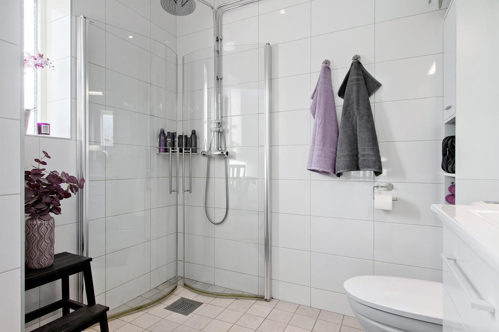 Badrum på nedre plan med dusch, skåp och kommod för förvaring.