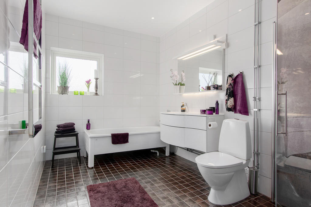 Rymligt fräscht badrum med både dusch och badkar Snygg kommod från Ballingslöv och belyst spegel