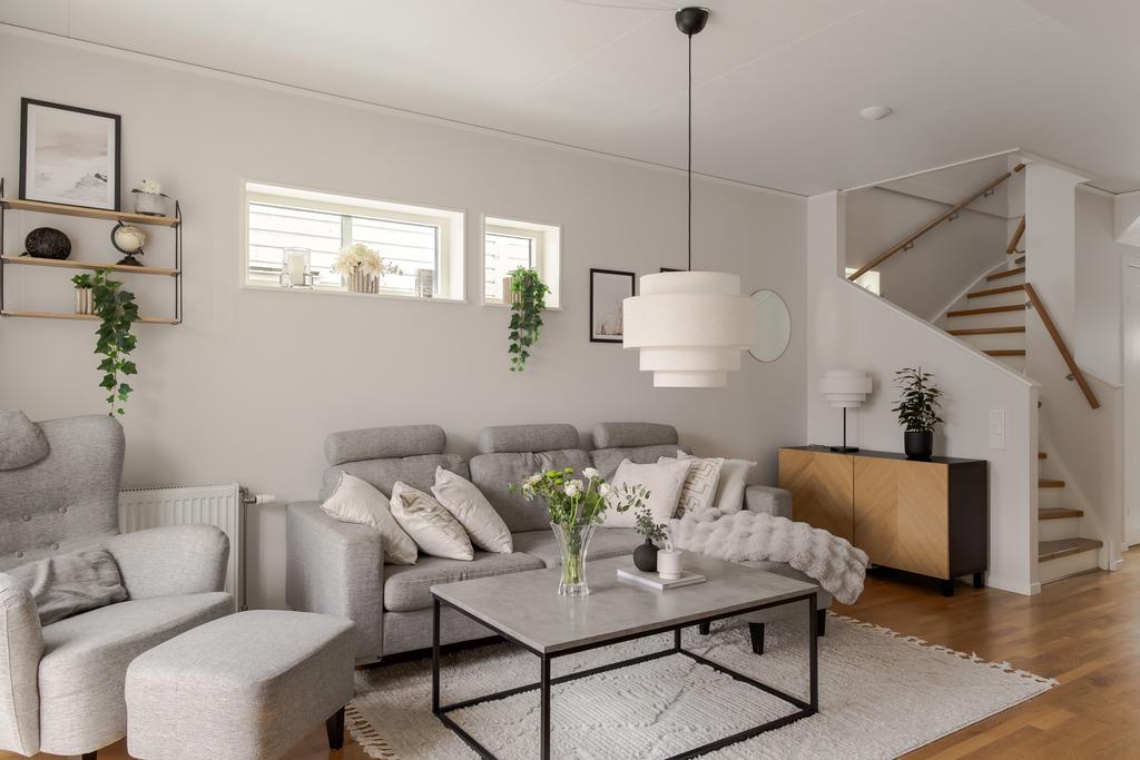 Vardagsrum med trappa till övre plan och naturlig samlingsyta.